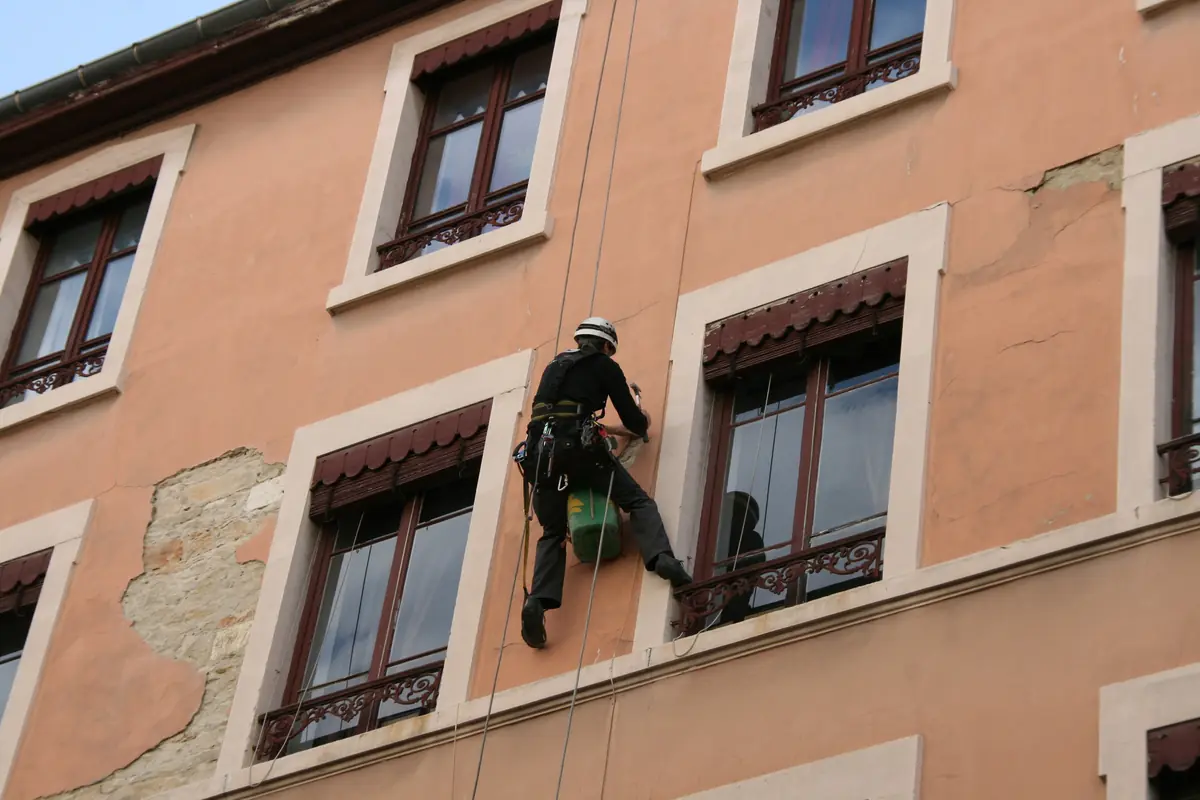 Alpinist utilitar lucrând pe o fațadă de clădire